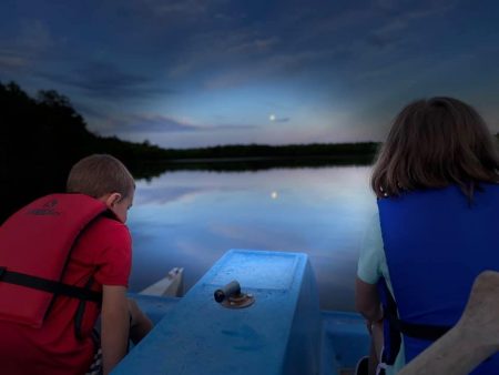 Two kids using paddle boat during sunset